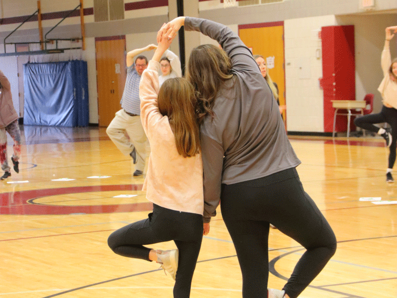 A mother and daughter join hands in the pigeon pose