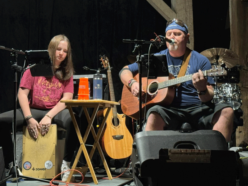 Two people perform music with guitar and drums