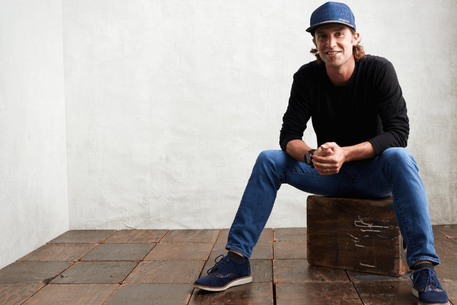 A young man sits on a wooden box facing the camera
