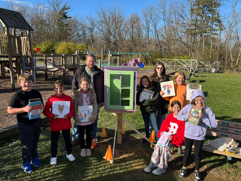 A group of staff and children stand outside a tranquility station holding books.